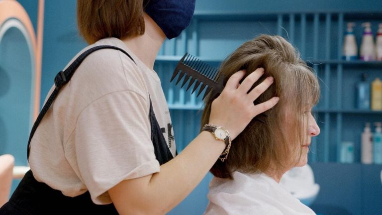 femme se fait brosser les cheveux chez le coiffeur