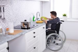 Homme en fauteuil roulant fait la vaisselle